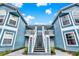 Charming condo complex with blue siding, white trim, and inviting staircase at 8716 Rain Forest Pl # D, Kissimmee, FL 34747