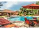 Large pool area with lounge chairs, tables, orange umbrellas, and a view of the surrounding buildings at 1375 Tuscana Ln # 1405, Davenport, FL 33896