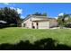 A view of the rear exterior of the home and the grassy backyard at 1843 Harbor Blvd, Kissimmee, FL 34744