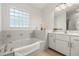 Bright bathroom featuring a soaking tub, glass block window, and a modern vanity with marble countertop at 1914 Ellery Ln, Kissimmee, FL 34746