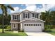 Charming two-story home with gray siding, stone accents, a well-manicured lawn, and a two-car garage at 223 Bull Frog Ln, Umatilla, FL 32784