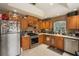 Kitchen featuring stainless steel appliances, wood cabinetry, tile flooring, and a gas range at 2912 Lazlo Ln, Orlando, FL 32837
