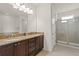 Bathroom featuring double sinks with granite countertops, dark wood cabinets, and a glass-enclosed shower at 340 Pendant Ct, Kissimmee, FL 34747