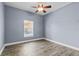 This bedroom has wood-look tile flooring, light-blue painted walls, and a lighted ceiling fan at 3427 Harborside Ct, Kissimmee, FL 34746