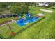 Aerial view of a community playground with modern equipment, picnic tables, and a beach volleyball court at 3427 Harborside Ct, Kissimmee, FL 34746