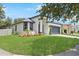 Landscaped front yard leads to a charming single-Gathering home with a gray roof and a two-car garage at 4903 Santa Clara Dr, Orlando, FL 32837