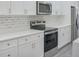 Modern kitchen with stainless steel appliances, white cabinets, stone countertops, and gray backsplash at 4903 Santa Clara Dr, Orlando, FL 32837