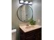 Bathroom featuring a round mirror, tan countertop, and modern lighting fixtures at 5826 Peregrine Ave # F01, Orlando, FL 32819