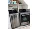 Well-lit laundry area with gray stainless steel washer and dryer and upper shelving for storage at 5826 Peregrine Ave # F01, Orlando, FL 32819