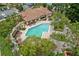 Aerial view of a community pool showcasing a tiled deck, lounge chairs, mature trees, and clubhouse at 7667 Sugar Bend Dr # 7667, Orlando, FL 32819