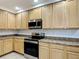 Well-lit kitchen featuring wooden cabinets, stainless steel appliances, and neutral countertops at 9055 Treasure Trove Ln # 207, Kissimmee, FL 34747