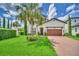 Charming home with a lush green lawn, a brick driveway, and a well-manicured landscape and a tropical palm tree at 10836 Royal Cypress Way, Orlando, FL 32836