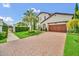 Beautifully landscaped home featuring a brick driveway, lush lawn, and an attached two car garage at 10836 Royal Cypress Way, Orlando, FL 32836
