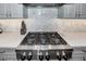 Close-up of a gas cooktop featuring a KitchenAid brand appliance and herringbone tile backsplash, and grey cabinets at 10836 Royal Cypress Way, Orlando, FL 32836