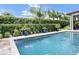 Beautiful pool with a water feature surrounded by manicured hedges and colorful potted plants at 10836 Royal Cypress Way, Orlando, FL 32836