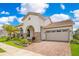 Charming stucco home with a tile roof, arched entrance, manicured lawn, and a brick-paved driveway at 13809 Abberwick Dr, Orlando, FL 32832