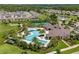 Aerial view of community pool, tennis courts, and clubhouse with lush landscaping at 17795 Blazing Star Cir, Clermont, FL 34714