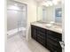 Modern bathroom with dual sinks, granite countertop, dark cabinetry, and a glass-enclosed shower at 1876 Summer Dr, Davenport, FL 33897