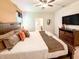 Comfortable bedroom features a ceiling fan, television, dresser, and many decorative pillows on the bed at 1876 Summer Dr, Davenport, FL 33897