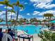 Large community pool surrounded by palm trees and colorful umbrellas, perfect for swimming and relaxation at 1876 Summer Dr, Davenport, FL 33897
