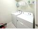 Functional laundry room with white washer and dryer, overhead shelving, and space-saving design at 1876 Summer Dr, Davenport, FL 33897
