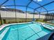 Screened-in pool and spa area with crystal-clear water, surrounded by a well-maintained fence and landscaping at 1876 Summer Dr, Davenport, FL 33897
