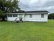 Exterior view of a white home with a weathered facade and green lawn at 1886 Pleasant Hill Rd, Kissimmee, FL 34746