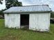 Run-down shed with peeling white paint and open doorway sits on a grassy lot at 1886 Pleasant Hill Rd, Kissimmee, FL 34746