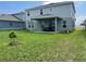 A spacious backyard with healthy grass, a covered patio, and a young tree in the landscape at 1896 Basenji Dr, Lake Alfred, FL 33850