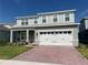 Charming two-story home features a brick driveway, neutral gray paint, and a two-car garage at 1896 Basenji Dr, Lake Alfred, FL 33850