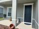 Inviting covered front porch with a dark blue door, potted plants, and stylish decor accents at 1896 Basenji Dr, Lake Alfred, FL 33850