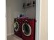 Functional laundry room features a modern, front-loading, red washer and dryer, with shelf at 1896 Basenji Dr, Lake Alfred, FL 33850