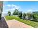 Landscaped backyard featuring a brick patio, well-manicured lawn, and lush greenery at 1951 Partin Terrace Rd, Kissimmee, FL 34744