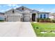 Attractive home featuring a 3-car garage, manicured lawn, stone accents, and freshly mulched garden beds at 1951 Partin Terrace Rd, Kissimmee, FL 34744