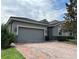 This home features a brick driveway, a gray two-car garage door, and attractive landscaping at 2016 Lakeside Ave, Davenport, FL 33837