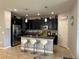 Modern kitchen features stainless steel appliances, dark cabinets, island with barstool seating, and pendant lighting at 2016 Lakeside Ave, Davenport, FL 33837