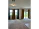 Spacious living room with plush carpet, large windows dressed with blue and yellow curtains, and a glass sliding door at 254 Mandovi St, Davenport, FL 33837