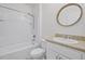 Bathroom with tub and shower combination, white tile, and round mirror at 3062 Royal Tern Dr, Winter Haven, FL 33881