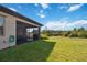 Spacious backyard with a screened patio area, lush green lawn, and privacy landscaping at 3224 Oxbow Ct, Harmony, FL 34773
