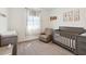 Bedroom with a grey crib, changing table, and comfortable armchair, bathed in natural light at 3224 Oxbow Ct, Harmony, FL 34773