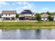 View of a home's backyard with a screened-in pool, white picket fence, and lawn extending to the lake at 3420 Middlebrook Pl, Harmony, FL 34773