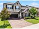 Charming two-story home with a brick driveway, stone accents, lush landscaping, and a two-car garage at 3420 Middlebrook Pl, Harmony, FL 34773