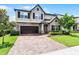 Charming two-story home with a brick driveway, stone accents, lush landscaping, and a two-car garage at 3420 Middlebrook Pl, Harmony, FL 34773
