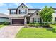 Charming two-story home with a brick driveway, stone accents, lush landscaping, and a two-car garage at 3420 Middlebrook Pl, Harmony, FL 34773