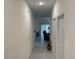 View down long hallway leading to living spaces with tile flooring and neutral paint at 3476 Yarian Dr, Haines City, FL 33844
