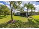 Expansive backyard with lush green lawn, mature trees, and a screened-in patio at 3606 Solana Cir, Clermont, FL 34711