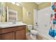 Bright bathroom featuring a wood vanity, toilet, and shower-tub with colorful curtain at 3606 Solana Cir, Clermont, FL 34711