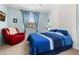 Cozy bedroom featuring stylish blue bedding, a relaxing red armchair, and decorative wall accents at 3606 Solana Cir, Clermont, FL 34711