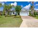 Beautiful single-story home featuring a manicured lawn, brick driveway, and lush landscaping under a sunny blue sky at 3606 Solana Cir, Clermont, FL 34711