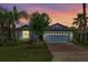 Charming single-story home featuring a brick driveway, manicured lawn, and lush tropical landscaping under a colorful twilight sky at 3606 Solana Cir, Clermont, FL 34711